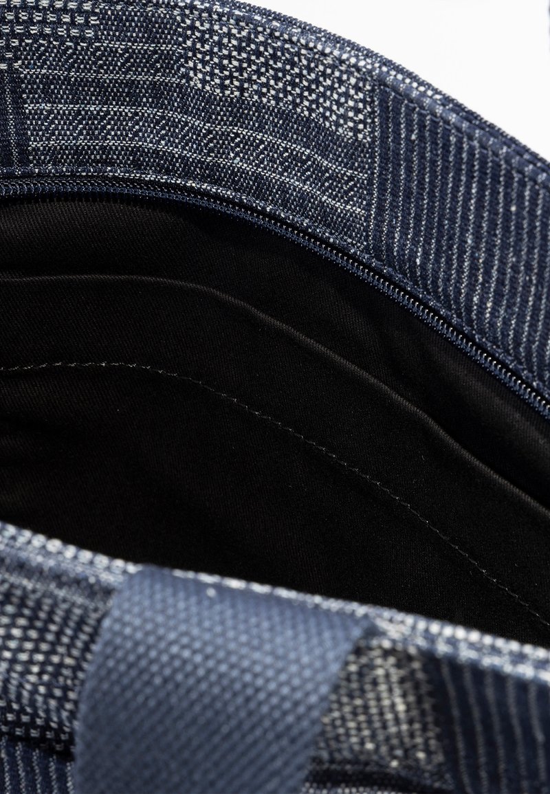 Borsa in tessuto blu con una trama intrecciata, dotata di una chiusura a zip e un interno nero liscio. I bordi presentano un design rinforzato e robusto.