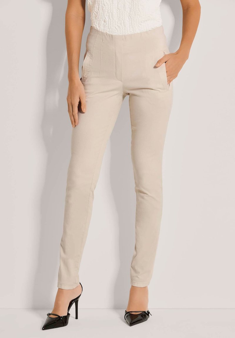 Beige, op maat gemaakte broek met een slim fit en zijzakken, gemaakt van een soepele stof. Gstyled met zwarte hoge hakken.