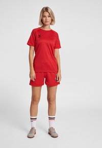 Rød sportsoutfit bestående af en åndbar, kortærmet top og matchende shorts. Funktioner inkluderer mesh-detaljer og kontrastfarvede grå detaljer.