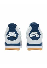 Zapatillas Nike SB, con una parte superior de cuero blanco, detalles en azul marino y suela de goma, con grandes logotipos en el talón. Detalles texturizados en toda su superficie.