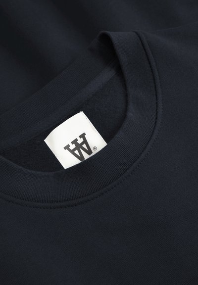 Sweat-shirt en coton marine avec un col rond côtelé, une texture douce et une étiquette centrale avec logo sur fond blanc.
