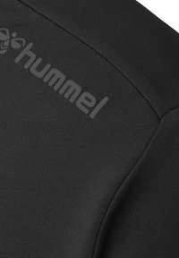 Sort stof med en glat tekstur, der har "hummel" logoet i grå, placeret på skrå på tøjet.