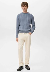 Jasnoniebieski sweter w prążki, kremowe spodnie i czarne skórzane kozaki. Sweter ma okrągły dekolt i teksturowaną tkaninę.