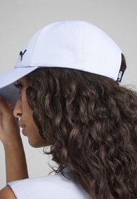 Cappellino azzurro chiaro con visiera curva, stile baseball. Presenta un logo nero sul davanti e un'etichetta laterale. Tessuto liscio e testurizzato.