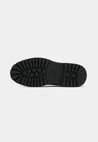 Black rubber shoe sole with deep treads, featuring a textured design and reinforced areas. The brand name is embossed on the side.