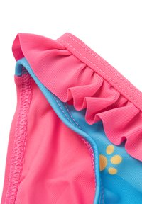 Costume da bagno per bambini con bordi arricciati rosa, tessuto blu con motivo di impronte di zampe e cuciture a contrasto lungo i bordi.