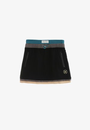 Falda en capas negra, gris y beige con cinturilla azul verdosa, bolsillos con cremallera y detalle de cordón, con un pequeño logo redondo en el frente.