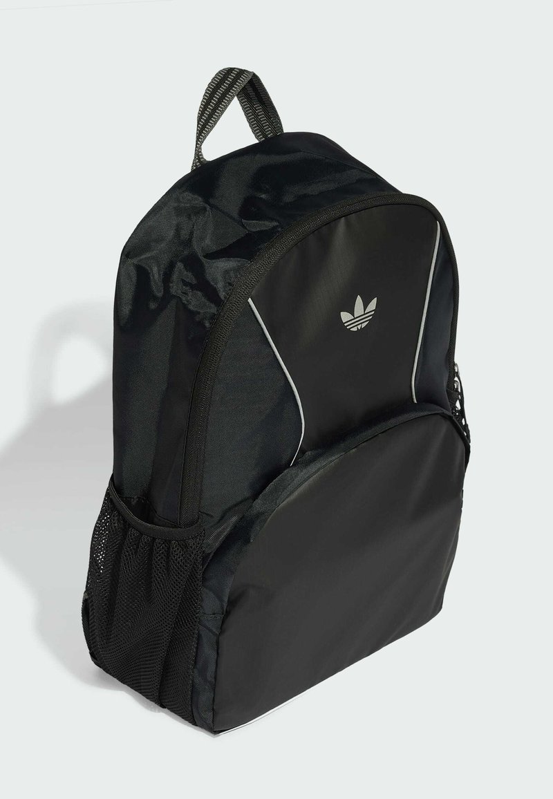 Schwarzer Adidas-Rucksack mit Netzseitentasche, vorderem Reißverschlussfach und Logo auf glatter Frontplatte vor hellem Hintergrund.