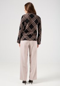 Top nero e beige con una trama a coste e maniche lunghe, abbinato a pantaloni a gamba larga beige chiaro e tacchi neri.