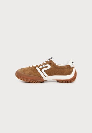 Brązowy zamszowy sneaker z białymi akcentami, białymi sznurówkami, gumową podeszwą i białym wzorem „P” z boku, pokazany z profilu na jednolitym tle.