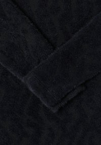 Tessuto nero con una superficie morbida e vellutata, caratterizzato da un motivo geometrico sottile e sezioni sovrapposte.