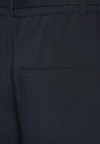 Námořnické kalhoty s texturovanou tkaninou, elastickým pasem a jednou zadní kapsou s obdélníkovým otvorem.