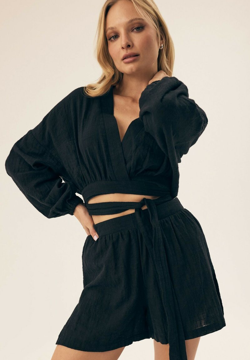 Czarny krótki top z luźnymi rękawami i owijanym fasonem, w zestawie z dopasowanymi szortami z wysokim stanem, które mają pasek do związania i fakturowaną tkaninę.