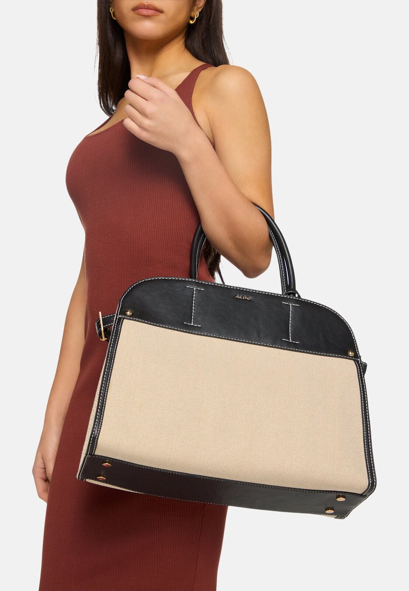 Structured handbag featuring a black leather top and beige canvas body with stitching accents. Dual top handles for carrying.