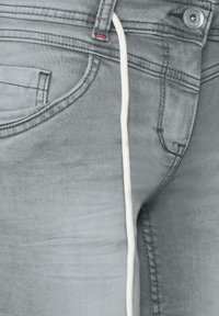 Jeans in denim grigio con una vestibilità slim, dotati di un laccetto bianco, una tasca frontale e dettagli di cucitura rossa sulla vita.