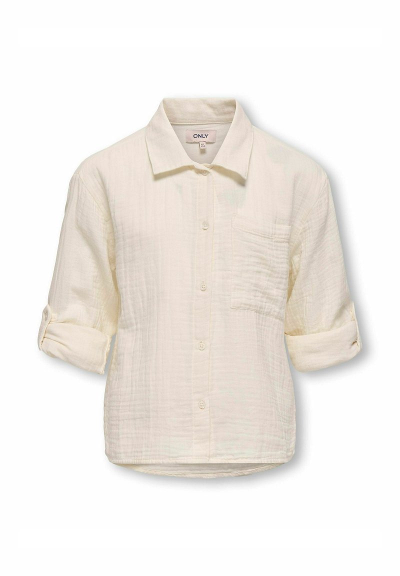 Krēmi krāsas pogājamā krekla mīksta, teksturēta auduma izpilde. Iespējas ir apkakle, krūšu kabata un sarullētas piedurknes.