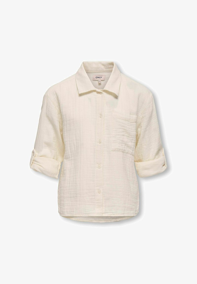 Krēmi krāsas pogājamā krekla mīksta, teksturēta auduma izpilde. Iespējas ir apkakle, krūšu kabata un sarullētas piedurknes.