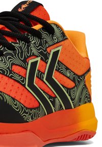 Sportovní bota s černým svrškem a zelenými konturovými linkami, oranžovými akcenty a texturovanou podrážkou. Černé tkaničky a logo na jazyku.