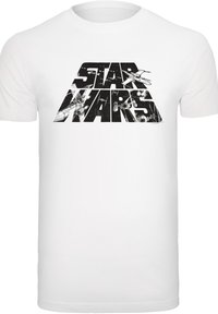 Balta kokvilnas t-krekls ar lielu, melnu "STAR WARS" logotipu, kuram ir sarežģīti grafiskie elementi, kas attēlo kosmosa kuģus burtiem.