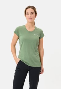 Groene T-shirt met korte mouwen, gemaakt van lichtgewicht stof, met een ronde hals en een klein logo bij de borst, gecombineerd met donkere broek.