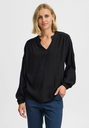 Schwarze Bluse mit langen Ärmeln, v-förmigem Ausschnitt, strukturiertem Stoff und gerafften Manschetten, kombiniert mit navyfarbener Hose. Lockere Passform und einfarbig.