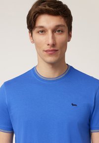 Blue cotton t-shirt with a crew neckline, short sleeves, and a small black dachshund embroidered on the left chest.