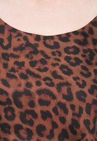 Látka s leopardím vzorom v teplých hnedých a čiernych odtieňoch, s hladkou textúrou a širokým, zaobleným výstrihom.