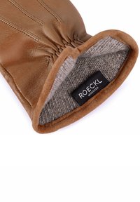 Brauner Lederhandschuh mit gerafftem Handgelenk. Weiche graue Fütterung und ein Etikett im Inneren mit der Aufschrift "ROECKL MÜNCHEN." Wildlederbesatz am Handgelenk.