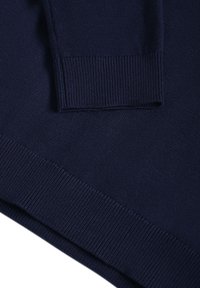 Tissu tricoté bleu marine montrant les détails des poignets et de la ceinture côtelés d'un pull à manches longues.