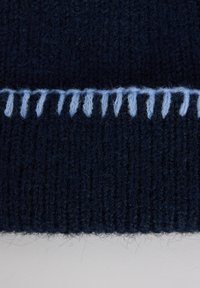 Navy blue knitted fabric features a textured pattern, with light blue contrasting stitching along the edge. Soft and warm appearance.