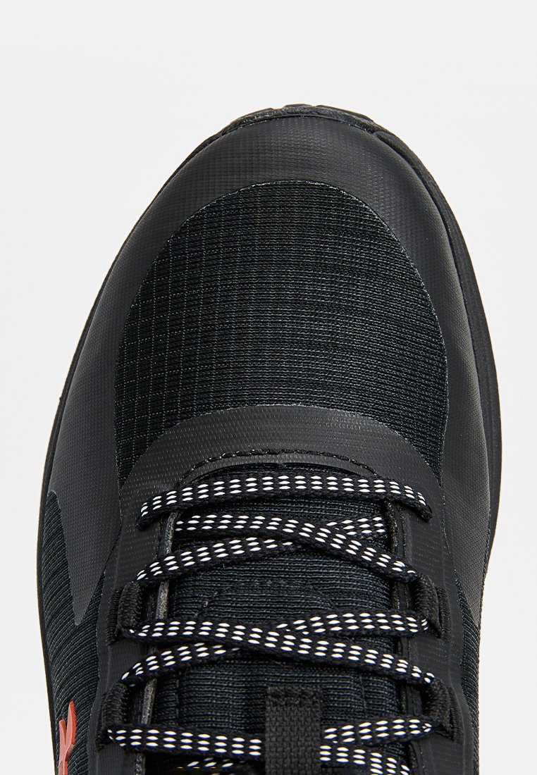 Chaussure de sport noire avec dessus texturé, dotée de lacets blancs et d'un accent rouge. Bout arrondi et talon renforcé pour un meilleur soutien.