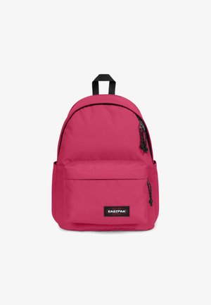 Pink fabric backpack with a rounded top, front zip pocket, adjustable straps, and a top handle. Features a black logo patch on front.