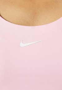 Roze sporttanktop gemaakt van een gladde stof, met een wit Nike-logo op de borst. Biedt een ronde halslijn en een aansluitend ontwerp.