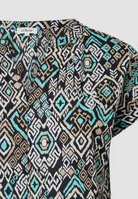 Korte mouwtop met een levendig patroon van zwarte, beige, aqua en witte geometrische ontwerpen op een lichtgewicht stof.
