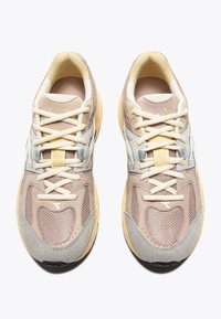 Pair of beige and grey athletic sneakers with mesh and suede details, cream laces, and cushioned yellow soles on a white background.