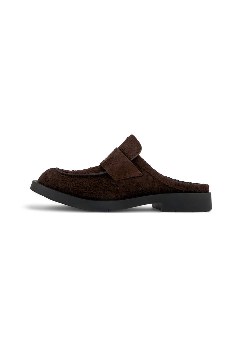 Pantofola mule con texture in pelliccia marrone, con un morbido upper e una fascia laterale. Presenta una suola nera piatta con una leggera curvatura e senza decorazioni visibili.