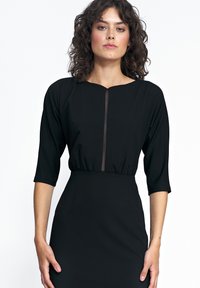 Czarna sukienka z rękawami do trzech czwarci, gładki materiał, okrągły dekolt, przezroczysty panel z przodu, dopasowana talia i spódnica sięgająca do kolan.