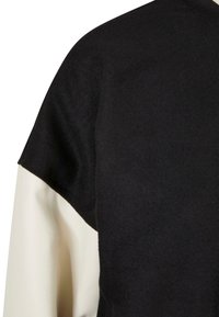 Čierny top s textúrovanou tkaninou, s krátkymi rukávmi a kontrastnou bielou podšívkou po boku. Jednoduchý, elegantný dizajn.