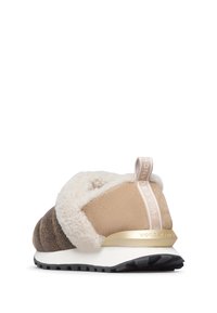 La scarpa presenta un mix di texture marrone e beige, tra cui suede e pelliccia sintetica, con una suola bianca e un tacco con dettagli dorati.