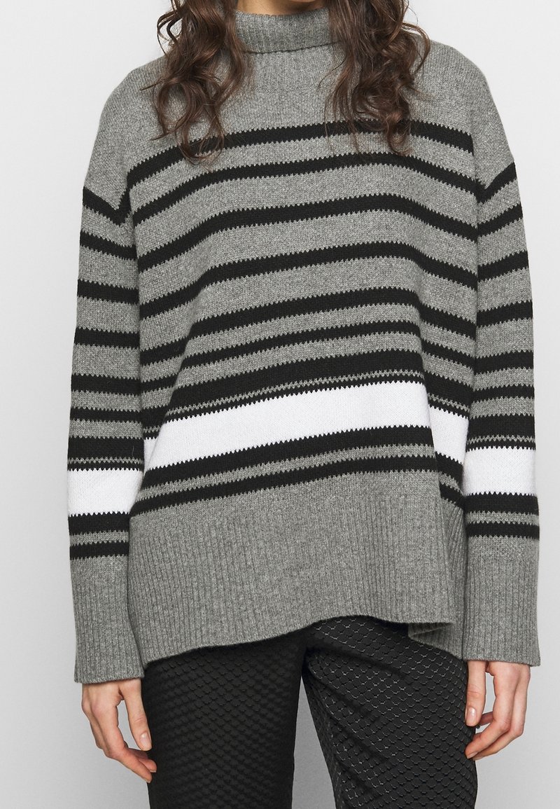 Szary i czarny sweter w paski z wysokim kołnierzem. Posiada grubą białą tasiemkę oraz ściągacz u dołu. Miękka dzianina o luźnym kroju.