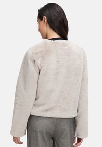 Beige faux fur jakke med en blød tekstur, afslappet pasform og lange ærmer. Har en rund hals og cropped kant, ideel til lagdeling.