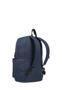 Mochila azul con tela acolchada, correas contorneadas, bolsillo lateral y un asa en la parte superior. Presenta un diseño simplificado y funcional.