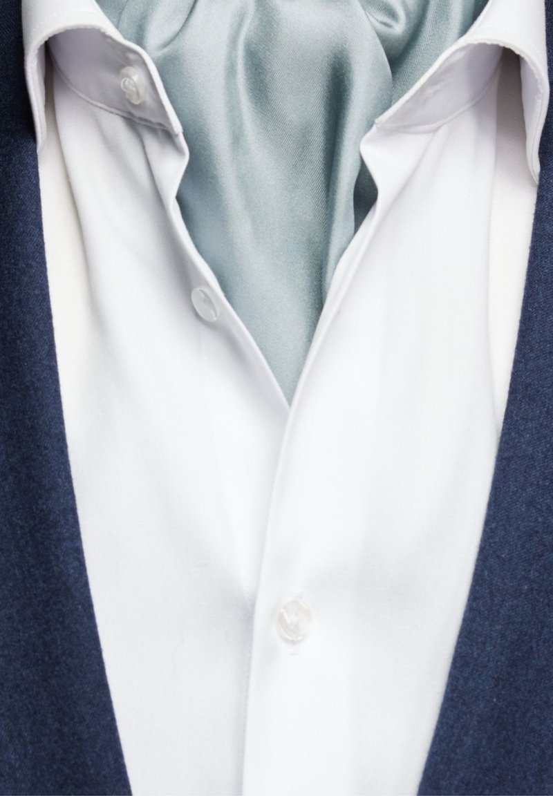 Vit skjorta med v-hals, prydd med en ljusblå satin scarf och en mörk marinblå jacka. Skjortan har knappstängningar och en slät yta.