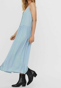 Vaaleansininen, hihaton maksimekkо, jossa on rypistetty vyötärö. Yhdistetty mustiin, teksturoituihin nilkkabootseihin, joissa on lohkarekorko.