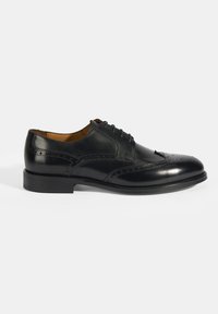 Zwarte leren dresschoenen met vetersluiting, brogue-details, ronde neus en lage gestapelde hak. Gladde textuur met een gepolijste afwerking.