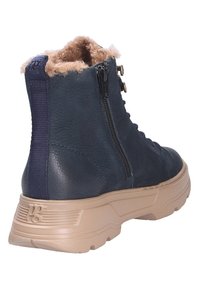 Botín de piel azul oscuro con forro de felpa beige, cremallera lateral y suela gruesa beige. Presenta material texturizado y cuello acolchado.