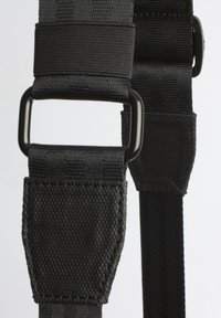 Cintura nera regolabile realizzata in nylon resistente, con cuciture rinforzate e fibbie in metallo per un attacco sicuro. Superficie testurizzata.