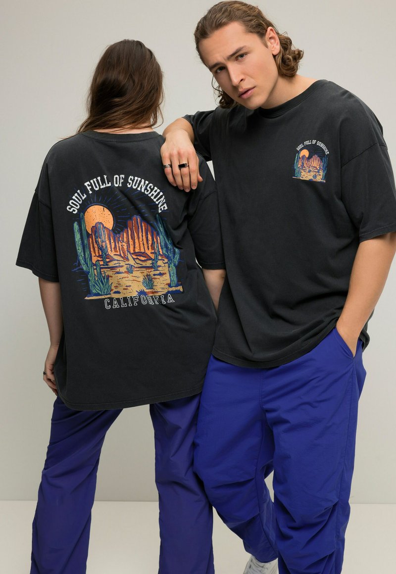 Zwarte oversized t-shirt met kleurrijke landschapafbeelding en de tekst "SOUL FULL OF SUNSHINE CALIFORNIA" op de achterkant en een kleine afbeelding op de voorkant.