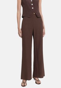 Bruine wijde broek van textuurstof, met een hoge taille, gladde afwerking en losse fit, gedragen met een bijpassende mouwloze top.