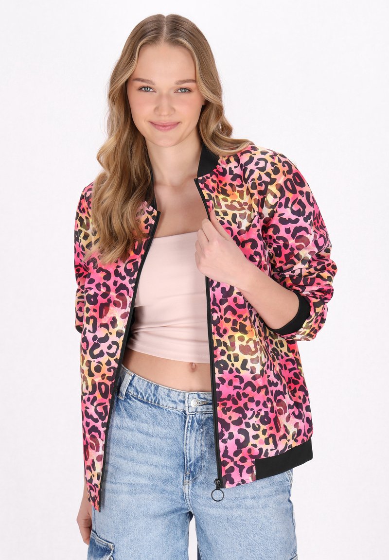 Jachetă bomber cu imprimeu leopard roz și portocalie, cu accente negre și manșete răsucite. Închidere cu fermoar, purtată peste un top roz deschis, asortată cu pantaloni scurți din denim.